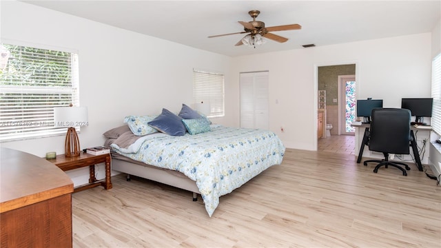 bedroom with light wood-type flooring, connected bathroom, ceiling fan, and a closet