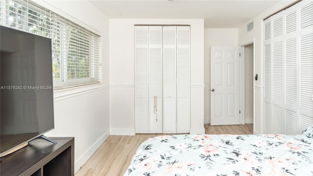 bedroom featuring multiple closets and light hardwood / wood-style flooring