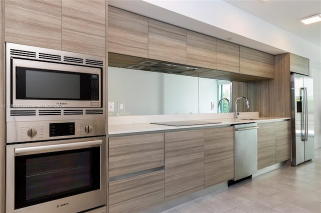 kitchen with sink, stainless steel appliances, and light tile floors