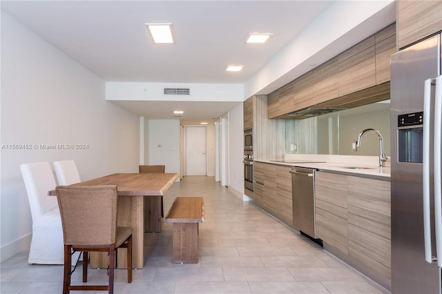 kitchen with stainless steel appliances, light tile floors, and sink