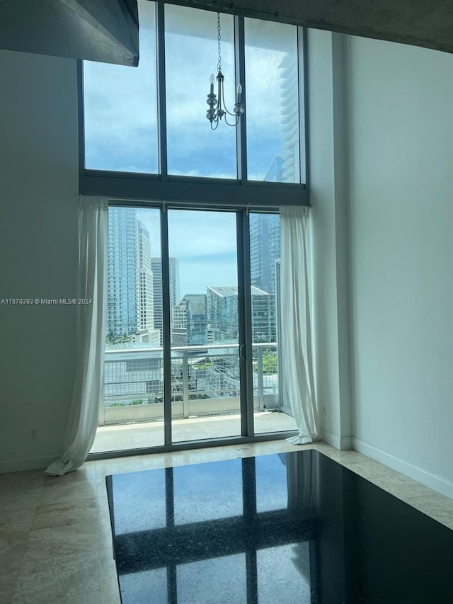 empty room featuring floor to ceiling windows, a notable chandelier, and tile patterned floors