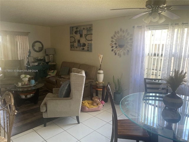 dining space with ceiling fan, a textured ceiling, and light tile flooring