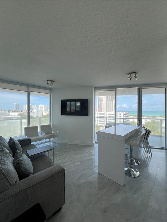 living room featuring a textured ceiling, expansive windows, and tile flooring