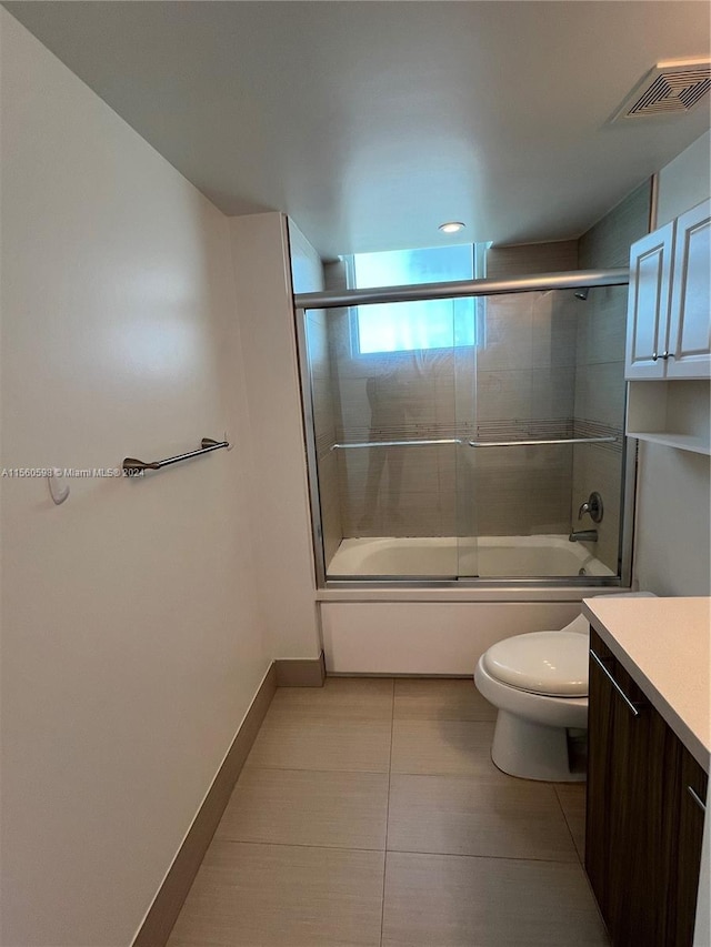 full bathroom featuring toilet, bath / shower combo with glass door, vanity, and tile flooring