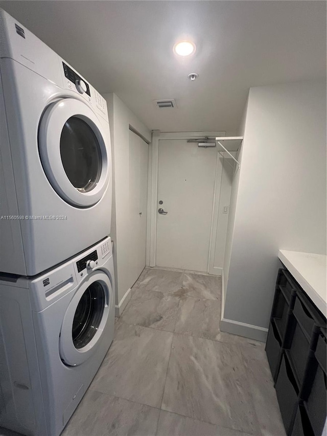 clothes washing area with stacked washer and dryer and light tile flooring