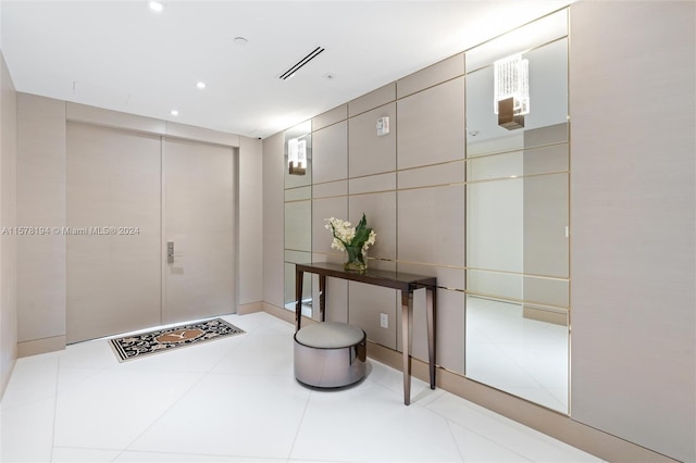 foyer entrance with light tile patterned floors and tile walls