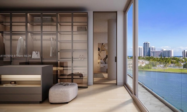 bedroom with a water view, expansive windows, and light wood-type flooring