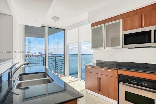 kitchen with dark stone countertops, sink, a water view, and appliances with stainless steel finishes