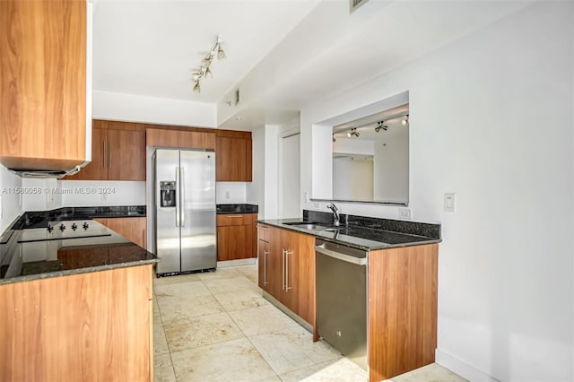 kitchen with dark stone countertops, sink, track lighting, and appliances with stainless steel finishes