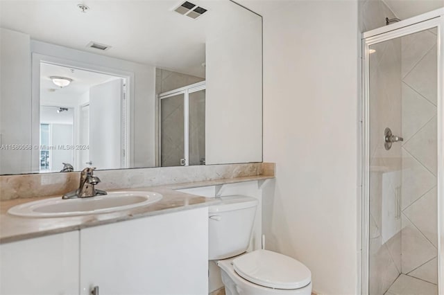 bathroom featuring vanity, an enclosed shower, and toilet