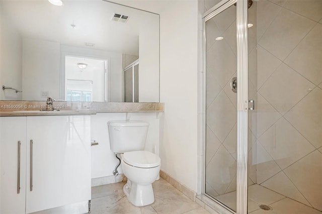 bathroom featuring tile patterned floors, vanity, toilet, and a shower with shower door