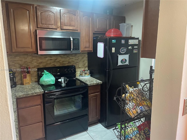 kitchen with tasteful backsplash, light stone countertops, light tile floors, and black appliances