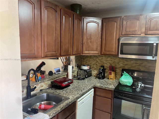 kitchen with light stone countertops, backsplash, white dishwasher, sink, and range with electric stovetop