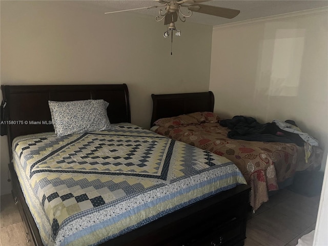 bedroom featuring hardwood / wood-style flooring, crown molding, and ceiling fan