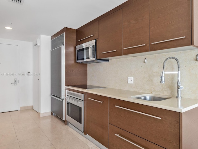 kitchen with tasteful backsplash, sink, light tile patterned floors, and stainless steel appliances