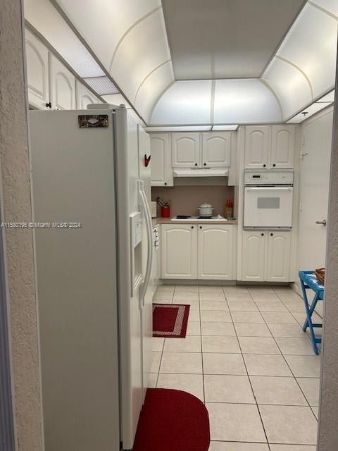 kitchen with white cabinetry, white appliances, and light tile floors