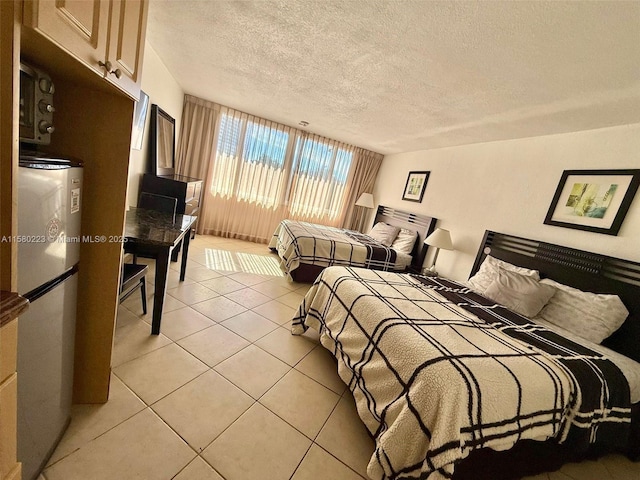 bedroom with light tile patterned floors, a textured ceiling, and stainless steel refrigerator