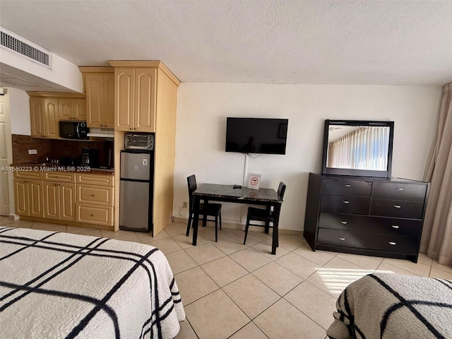 bedroom featuring a textured ceiling, stainless steel refrigerator, and light tile patterned flooring