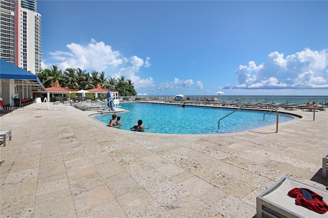 view of swimming pool with a water view and a patio