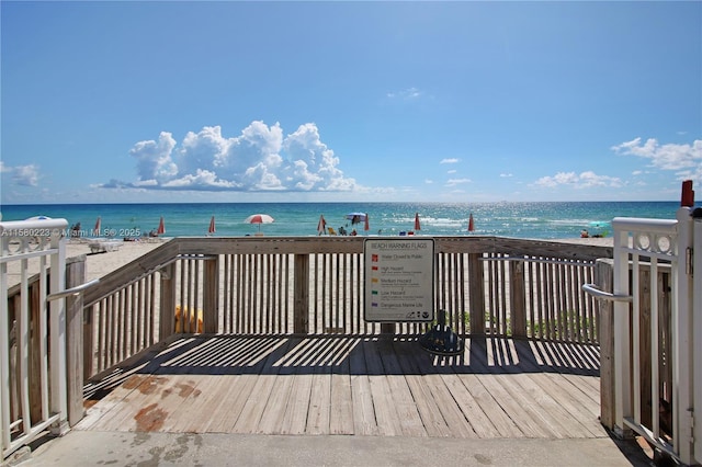 wooden deck with a water view and a view of the beach