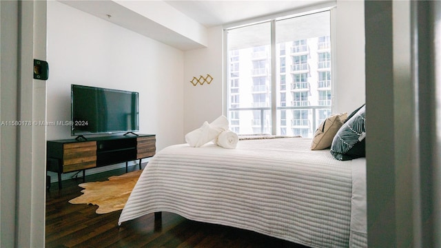 bedroom with dark hardwood / wood-style flooring and a wall of windows