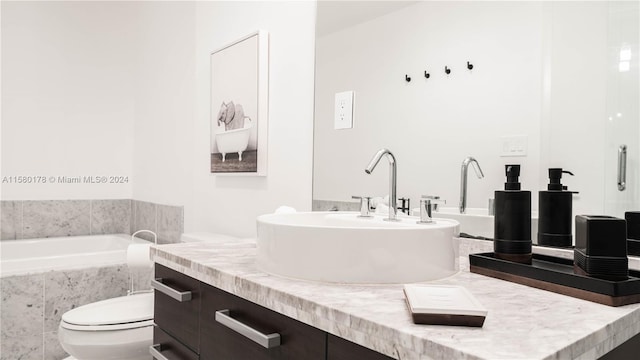 bathroom featuring tiled tub, vanity, and toilet