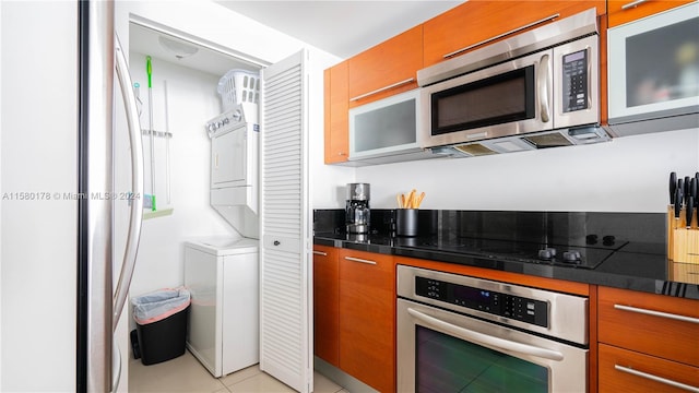 kitchen with appliances with stainless steel finishes, dark stone counters, and light tile floors