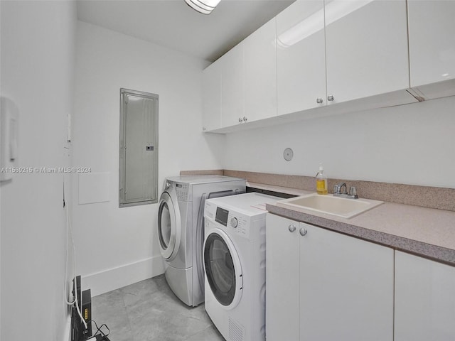 clothes washing area featuring cabinets, sink, light tile flooring, and washer and dryer