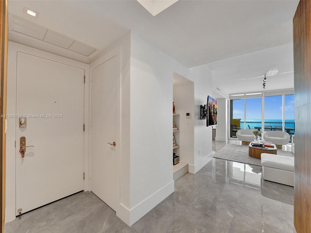 corridor with light tile flooring, floor to ceiling windows, and a water view