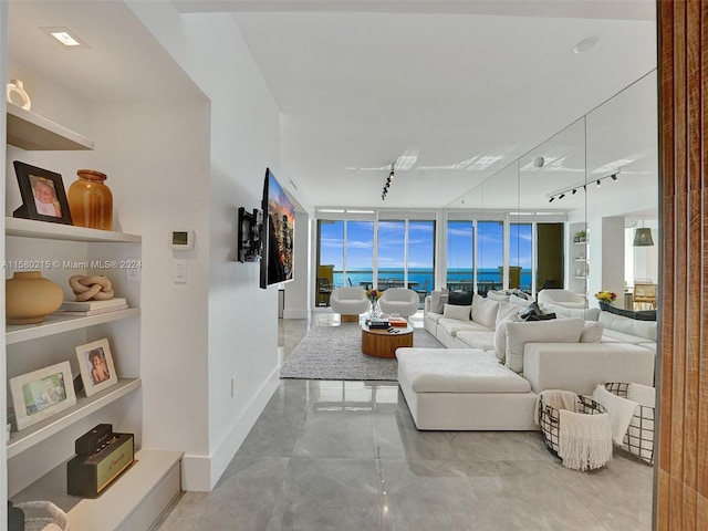 tiled living room with floor to ceiling windows, track lighting, and a water view