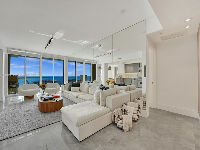 living room featuring floor to ceiling windows, a water view, and rail lighting