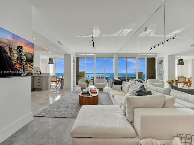 tiled living room with expansive windows, a water view, and track lighting