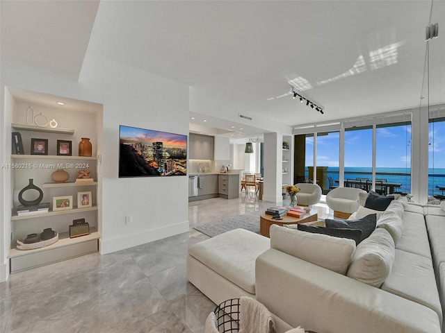 tiled living room with sink, a wall of windows, a water view, and rail lighting