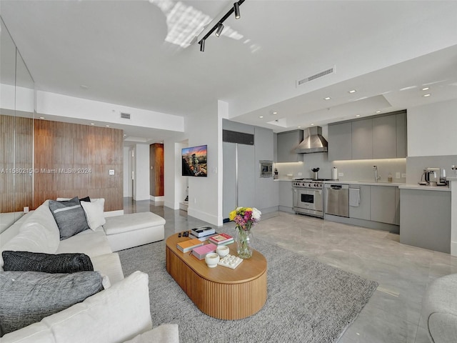 living room featuring rail lighting and sink