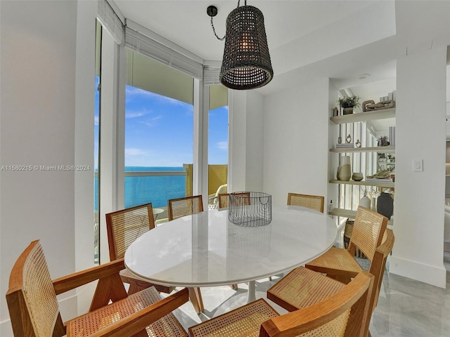 dining room featuring a healthy amount of sunlight, a water view, and light tile floors