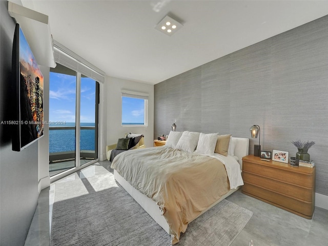 bedroom featuring a water view, floor to ceiling windows, and access to exterior