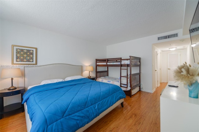 bedroom with light hardwood / wood-style floors and a textured ceiling