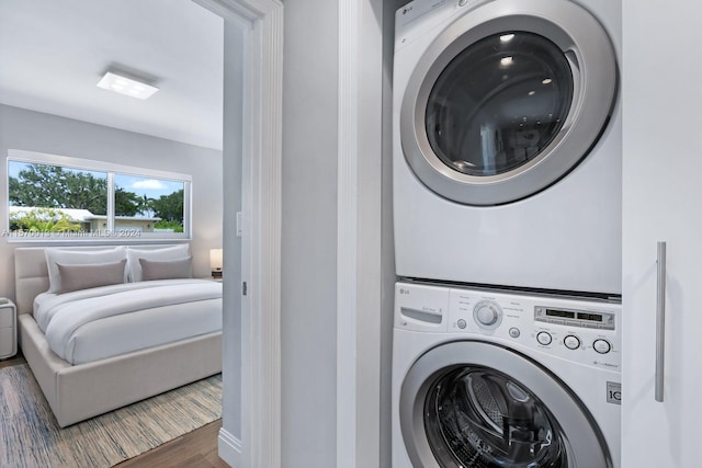 washroom featuring stacked washer and dryer and dark wood-type flooring