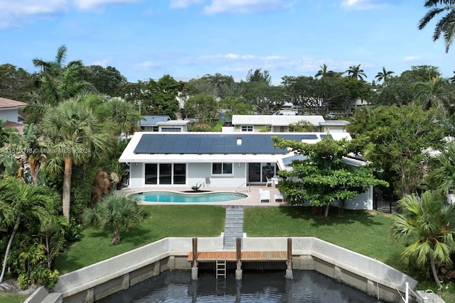 rear view of house featuring a lawn, a water view, a patio area, and solar panels