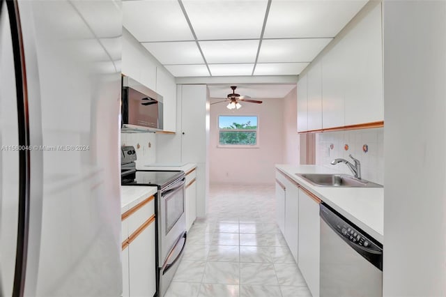 kitchen featuring light countertops, decorative backsplash, appliances with stainless steel finishes, white cabinetry, and a sink