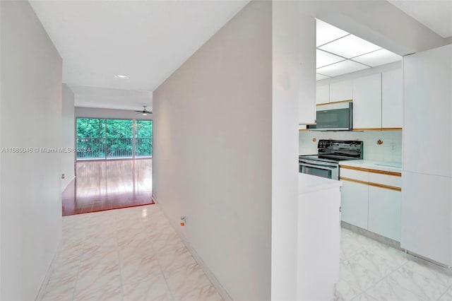 kitchen with marble finish floor, stainless steel appliances, light countertops, backsplash, and white cabinets