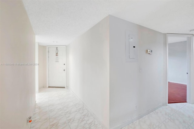 corridor with a textured ceiling, electric panel, and baseboards