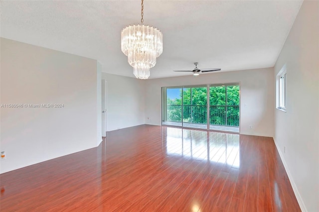 empty room featuring ceiling fan with notable chandelier and wood finished floors