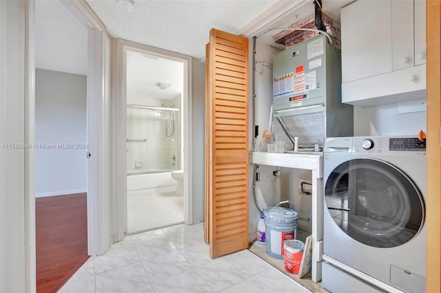 washroom featuring a textured ceiling, washer / clothes dryer, and cabinet space