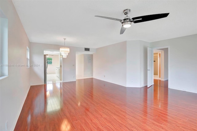 unfurnished room featuring ceiling fan with notable chandelier, wood finished floors, and visible vents