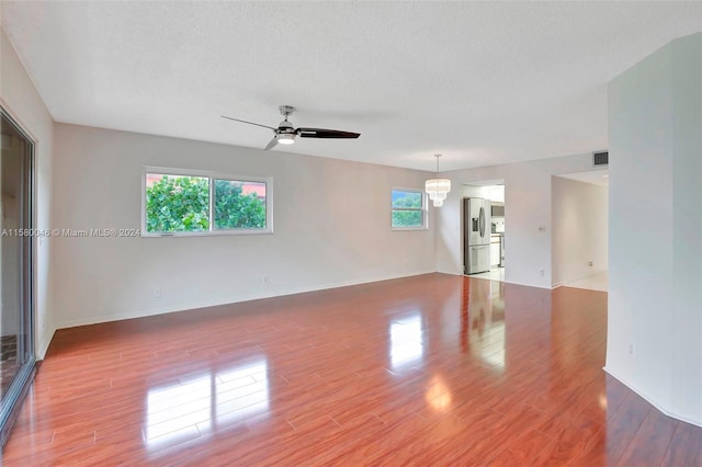 spare room featuring a ceiling fan, visible vents, a textured ceiling, and wood finished floors