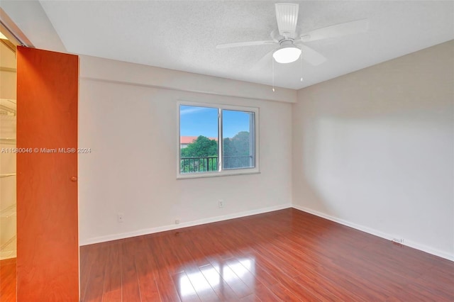 spare room with a ceiling fan, a textured ceiling, baseboards, and wood finished floors