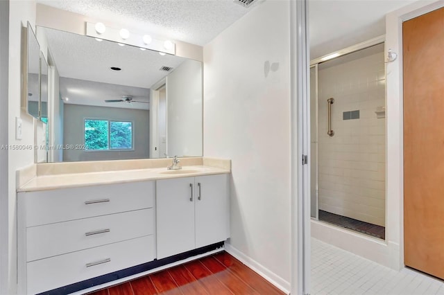 bathroom with a textured ceiling, wood finished floors, vanity, baseboards, and a shower stall