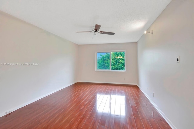 spare room featuring a ceiling fan, a textured ceiling, baseboards, and wood finished floors