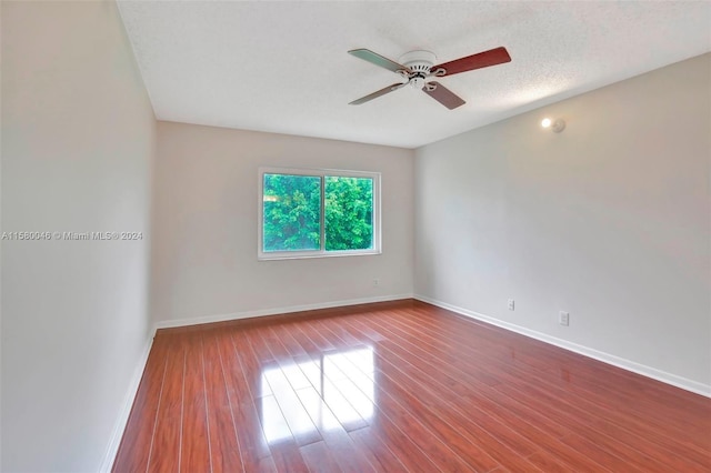 spare room with a ceiling fan, a textured ceiling, baseboards, and wood finished floors